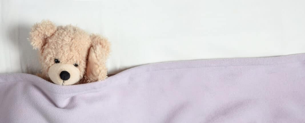 Headache, insomnia. Cute teddy in bed, holding his head, banner, copy space