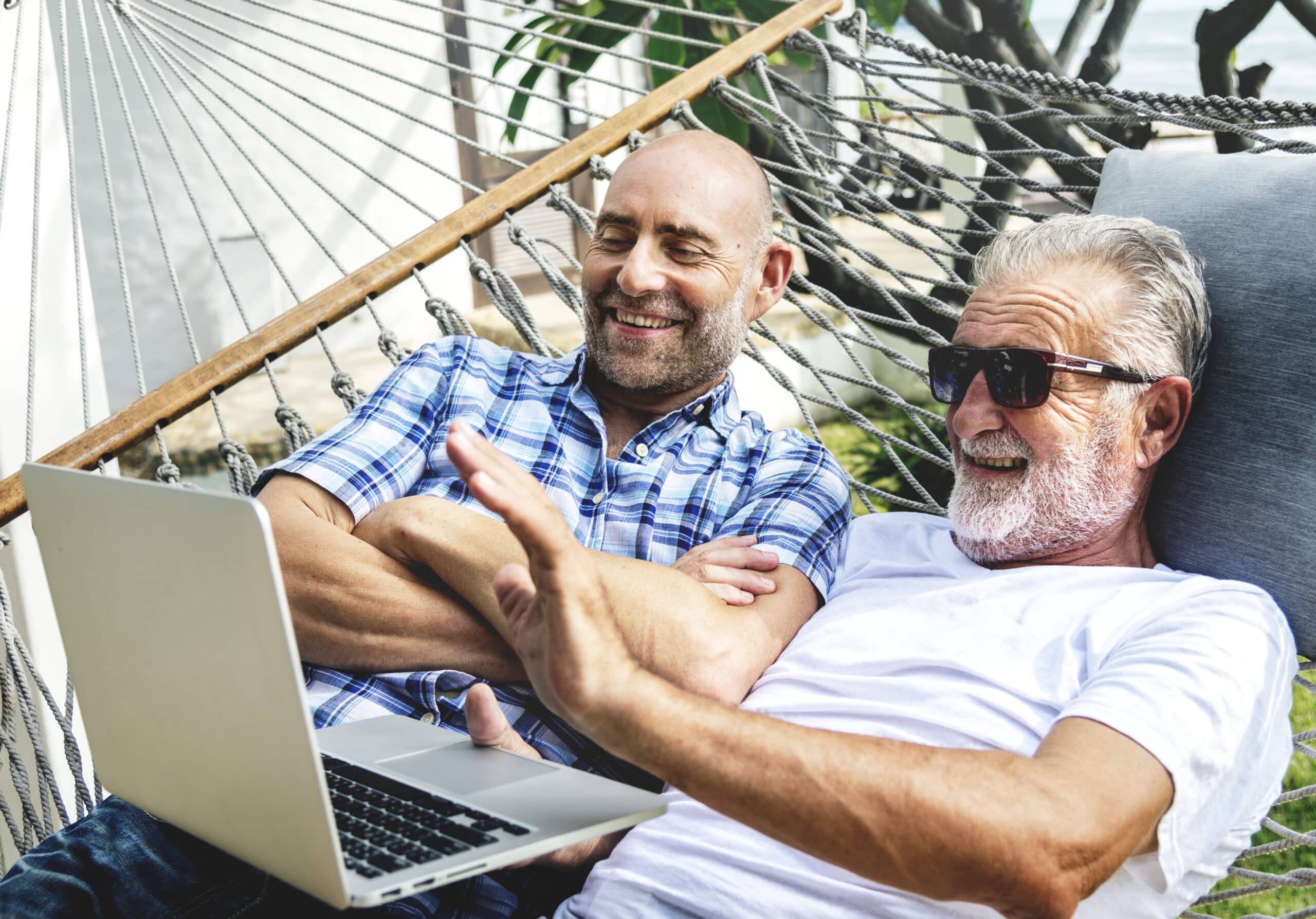 Senior men lying on a hammock using a laptop