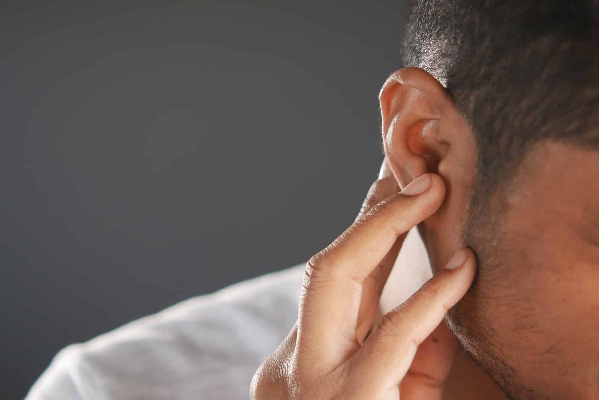 young man having ear pain touching his painful ear ,