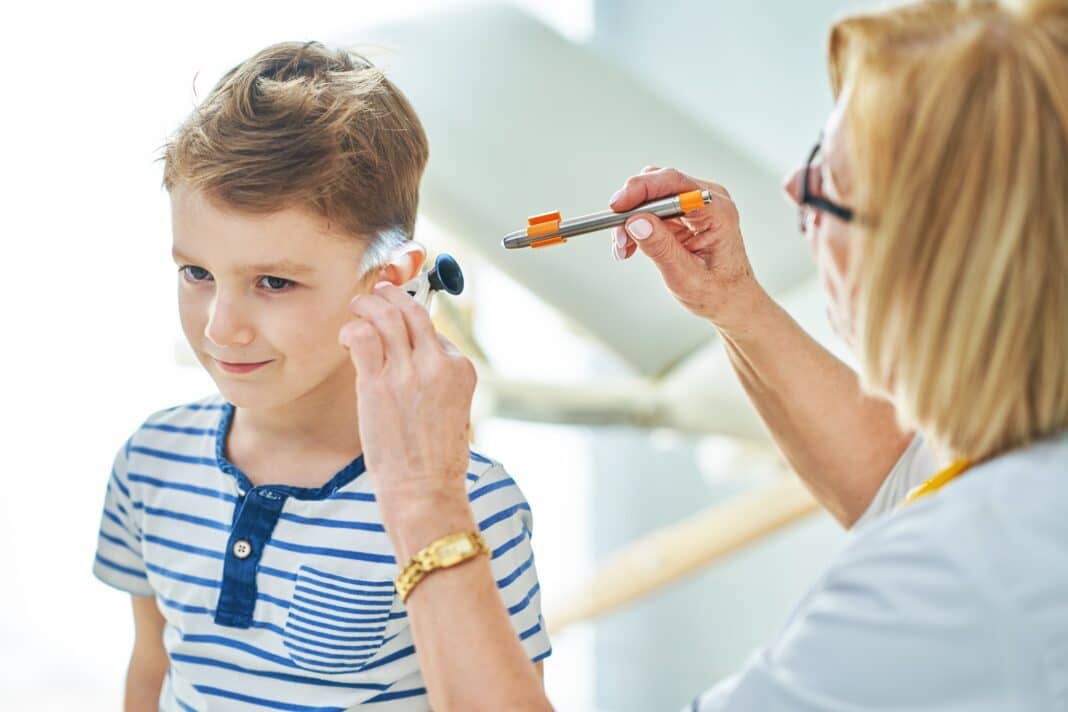 Pediatrician doctor examining little kids in clinic ears check