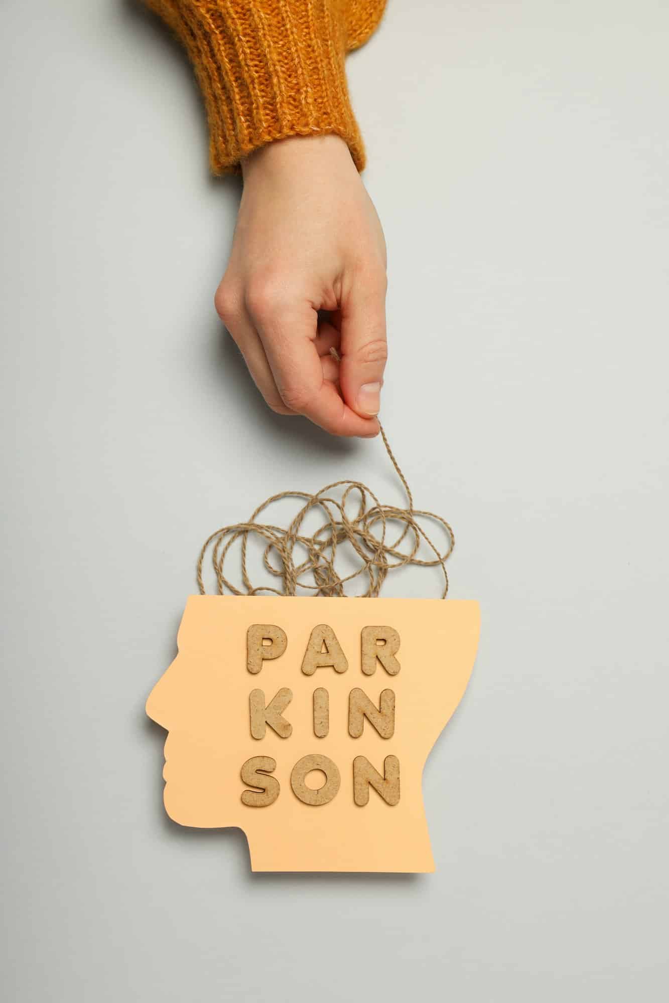 Paper head and female hand with twine on gray background