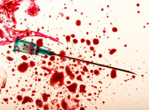 Studio shot of medical needle and blood drops